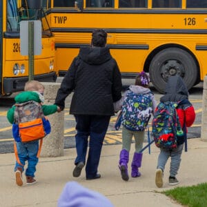 three students walk to their bus